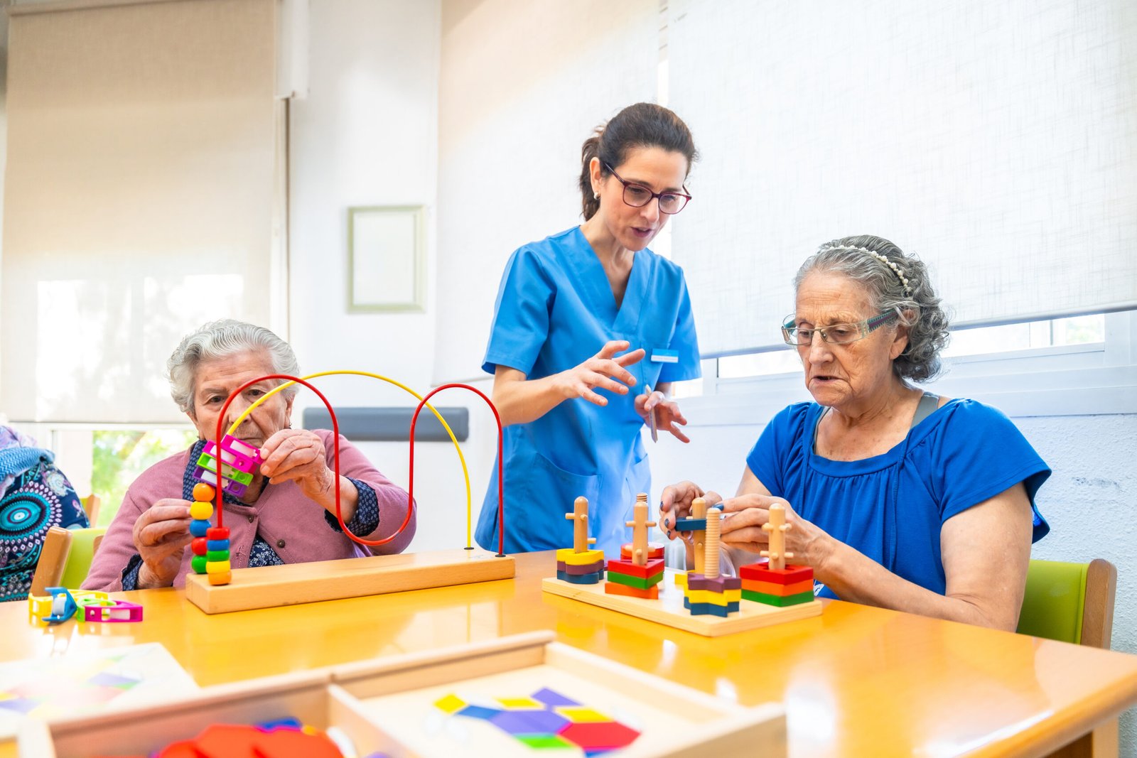 Cuidadora guiando juegos de estimulación cognitiva con personas mayores en el hogar
